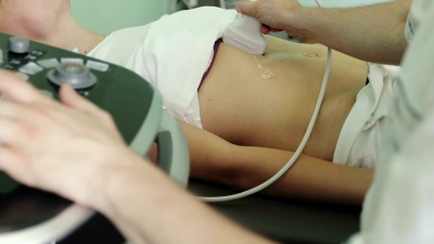 男医生使用超声波扫描仪检查女性的腹部器官。