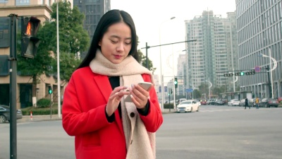 美丽的亚洲女孩使用智能手机在现代城市
