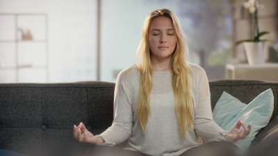 美丽的年轻女士以轻松的姿势坐在沙发上