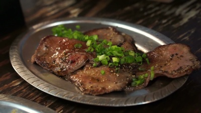 日式烧烤牛肉舌片在盘子上加柠檬在Izakaya餐厅风格