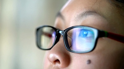 女孩眼睛戴眼镜看电脑显示器，上网或社交媒体