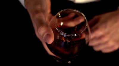 溅着白兰地的玻璃，慢动作。男人手里拿着一杯白兰地。