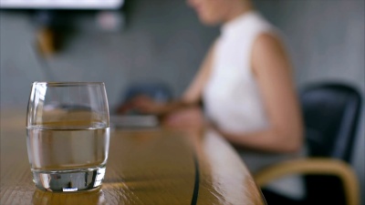 玻璃杯里的水和女商人在办公桌上使用笔记本电脑