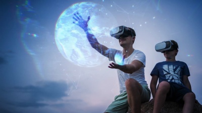坐在室外使用VR头戴式耳机观看地球全息图