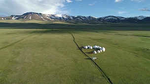 阳光灿烂的夏日，山谷和山脉中的蒙古包在背景上。鸟瞰