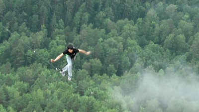 在西伯利亚自然保护区斯托尔比，一名男子走在两座山峰之间的一条绳子上。