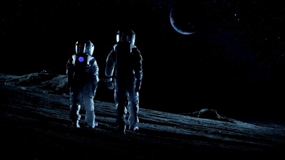 由两名穿着太空服的宇航员组成的机组人员站在外星人星球上，看着这个可能适合居住的星球。月球殖民和太空旅行的高科技概念。
