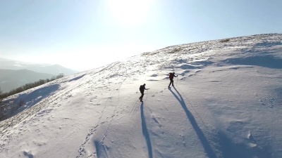 两个人在白雪覆盖的山上爬山