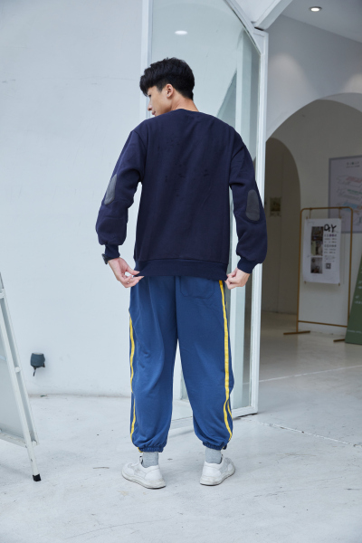 服饰系列实景模特穿着黑色卫衣和蓝色条纹运动裤的街头摆拍  