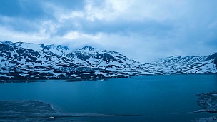 延时摄影的云在黄昏蓝时，湖泊和白雪覆盖的山峰