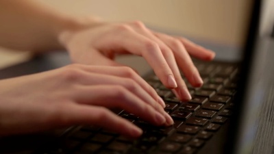 程序员的女人用笔记本电脑打字。把注意力放在他的手指上