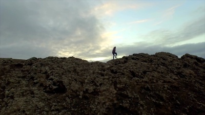 空中 在火山口边缘徒步旅行的女人