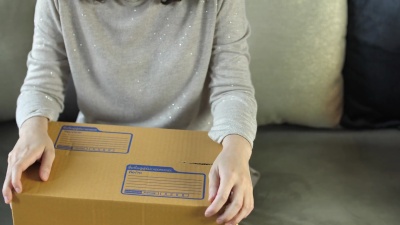 年轻女子打开纸板箱在家享受购物