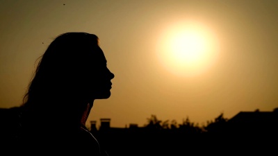 乡村背景下在散射的夕阳下摆姿势的女人的黑色剪影的侧视图