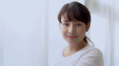 美丽的肖像年轻的亚洲女子早上醒来后看着窗外的卧室，女孩以微笑和快乐放松，生活理念，慢动作。