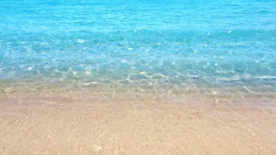 阳光明媚的热带海滩海岸线，沙滩和波浪到达