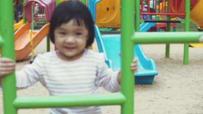 亚洲女婴正享受着在操场上攀爬和玩器械的乐趣