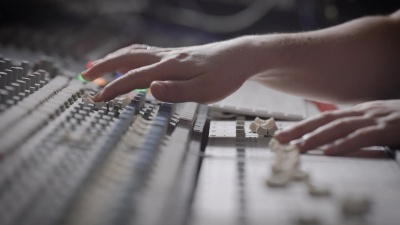 一位音乐家在音乐工作室的音频混音台上工作的侧视图快照