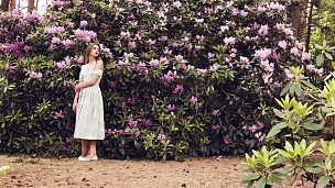 女孩站在开花的树丛中。