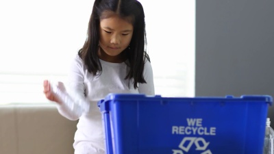 年轻女孩把瓶子放进回收站