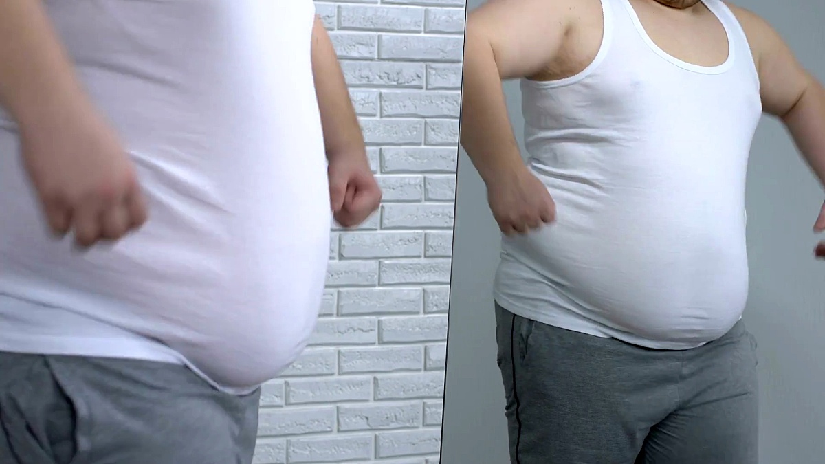 肥胖年轻人在镜子前摆姿势，假装肌肉，健身和节食