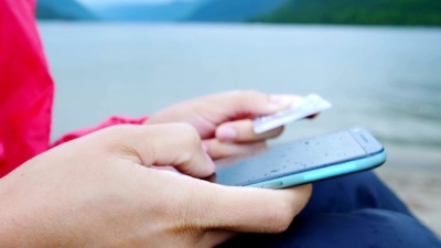 闭上手，手持信用卡，在户外使用移动智能手机。