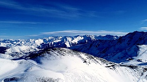 飞下雪山顶的滑雪场。在法国，阳光明媚的一天，鸟瞰山脉。冬天令人放松的白色风景。
