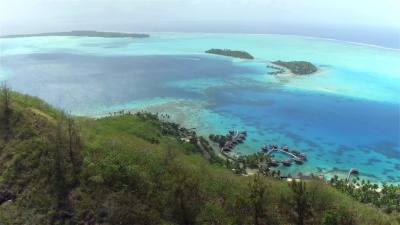 空中 位于隐蔽的热带白色沙滩上的豪华海滨酒店度假村，巨大的无限大游泳池和豪华的水上别墅，隐蔽的住宿地点位于法属波利尼西亚的一个美丽的异国情调的岛屿博拉岛上。