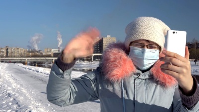 一个戴着口罩的女人，在冬天吸烟的烟斗的背景下。