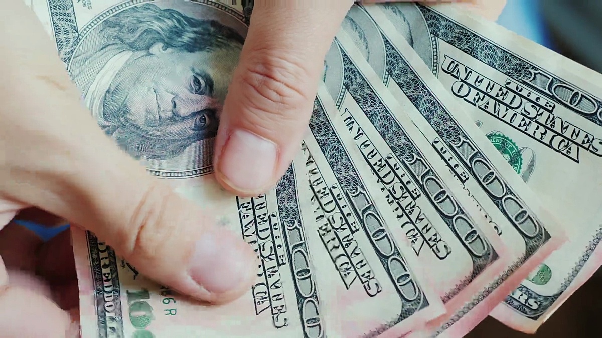 男人的手指看着美元钞票。钱被粉色油漆损坏了