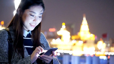 年轻的亚洲女性在现代城市玩手机