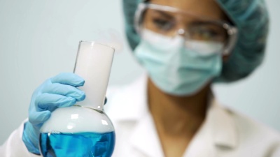 女化学家手持蓝色蒸发液烧瓶，实验