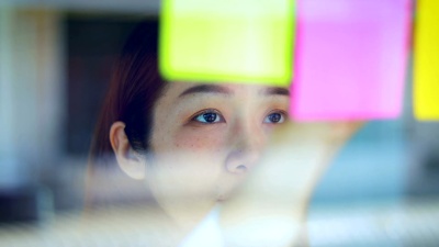 女商人把计划和约会贴在玻璃墙的便利贴上