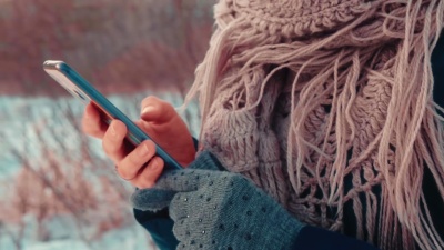 特写侧视图，无法辨认的女人的手在自然模糊的背景下在手机上打字