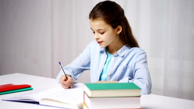 快乐的女学生在家把书写到笔记本上