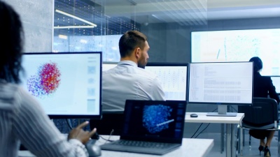 多种族的计算机科学家团队在他们的工作站上创建神经网络。Office充满了显示神经网络的3D表示的显示器。