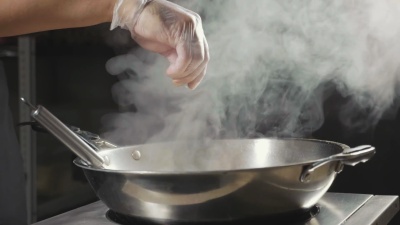 厨师在煎锅里倒入调味料的特写镜头，慢动作。