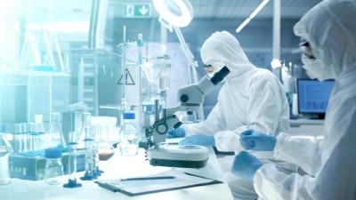 在一个安全的高级实验室里，科学家们在一个整体上进行研究。化学家用钳子调整培养皿中的样品，然后在显微镜下检查，他的同事写下结果。