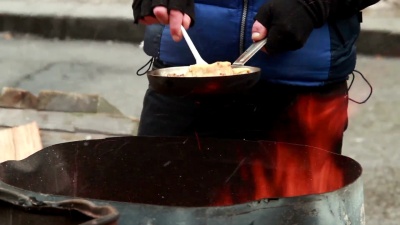 男性炸薯条在平底锅上用餐，冬天在户外，塑料叉子，没有