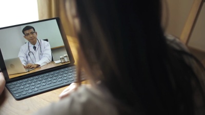生病的妇女在家里的平板电脑上与医生进行视频对话
