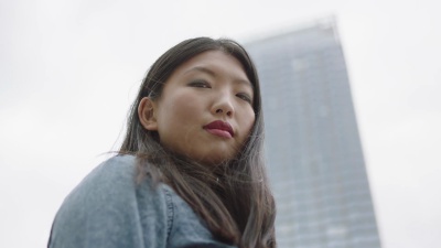站在摩天大楼旁边的年轻女子