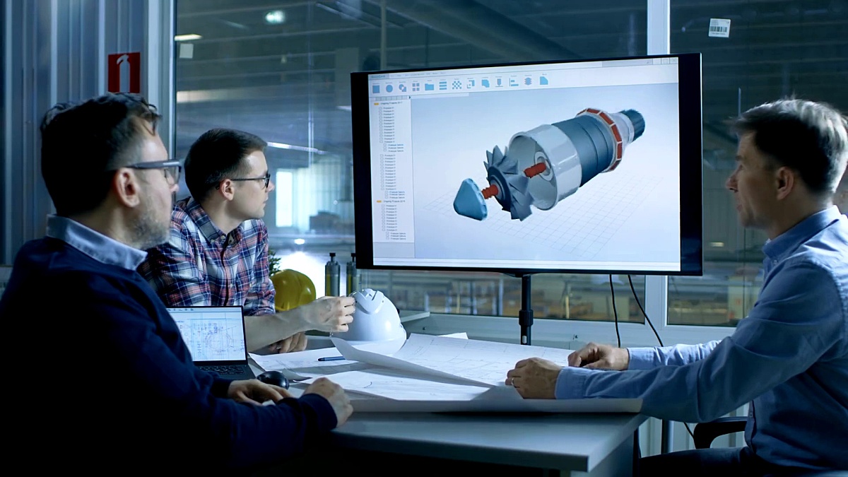 工业工程师团队讨论在演示展示上显示的涡轮/发动机设计的3D模型。在背景中可以看到工厂。