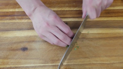 用手在木制砧板上切百里香