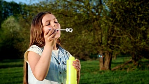 快乐的孩子在春天公园吹肥皂泡泡。慢动作