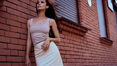 可爱漂亮的拉丁女人穿着礼服靠着砖墙摆姿势