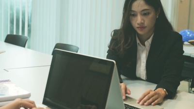 在办公桌前用电脑键盘工作的年轻女子。