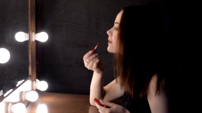 美丽的女性侧面画着坐在镜子前的嘴唇