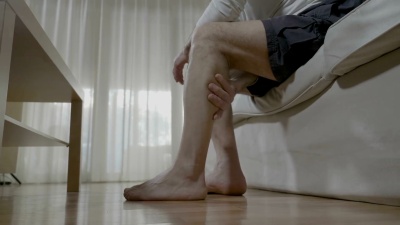 老人在疲惫的双腿上做自己的按摩疗法，缓解家里的疼痛和压力