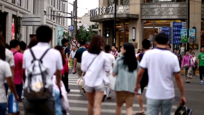 在城市街道的斑马线上行走的行人，实时。