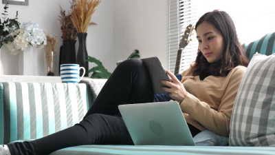 在沙发上使用笔记本电脑在家工作的女性